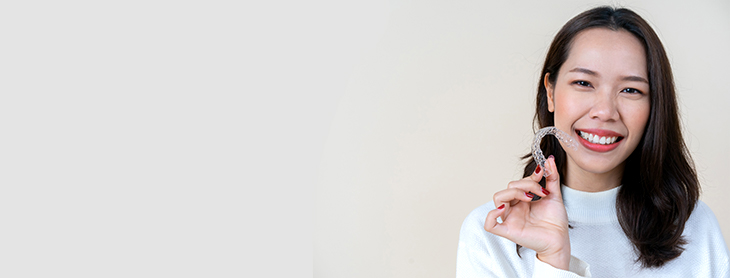 Smiling woman holding up a mouthguard