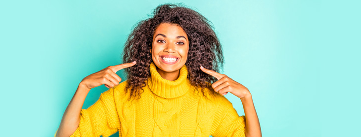 Woman smiling and pointing to her teeth