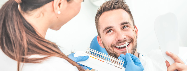 Dentist showing male patient options for implants